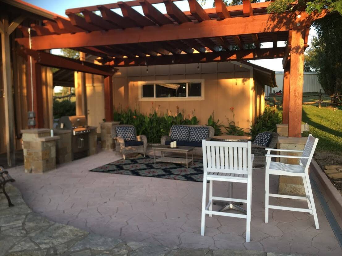Pergola-covered patio with an outdoor grill, seating and stamped concrete