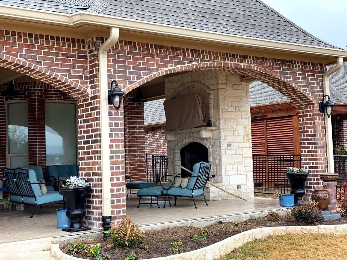 Brick arches over a covered patio with a stone fireplace and seating