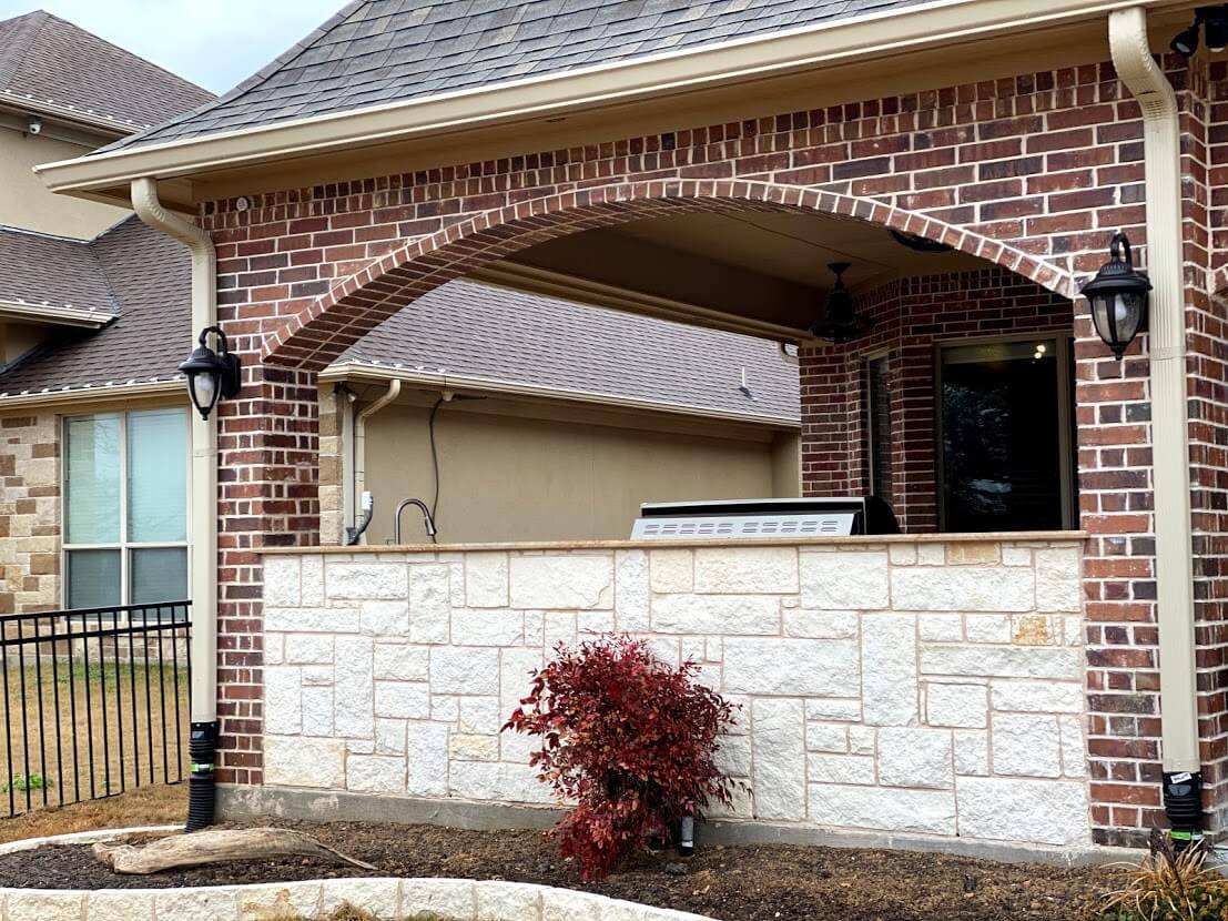 Stone outdoor kitchen counter under a brick arch