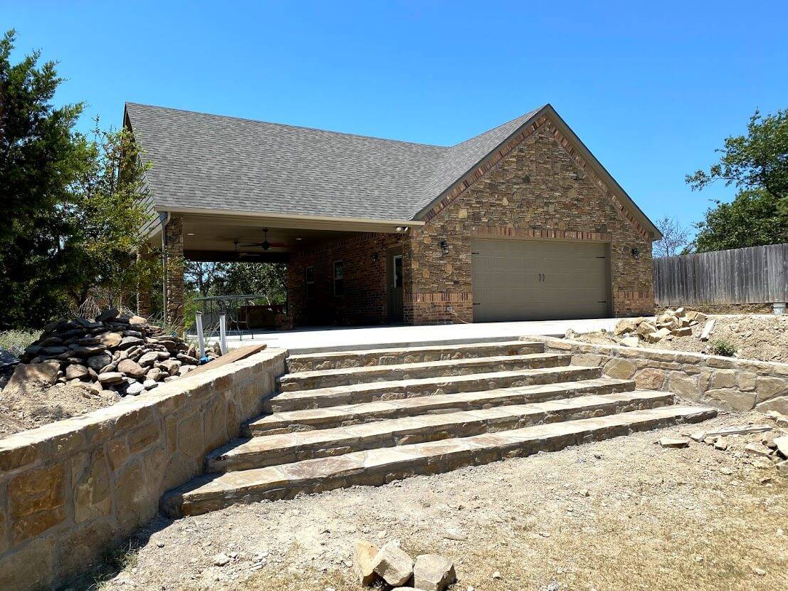 Stone and brick garage with a wide set of stone steps and retaining walls