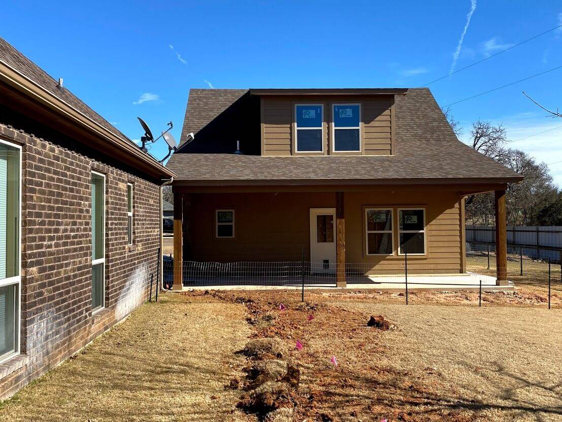 Rear of a home with a covered back porch and two dormer windows above it