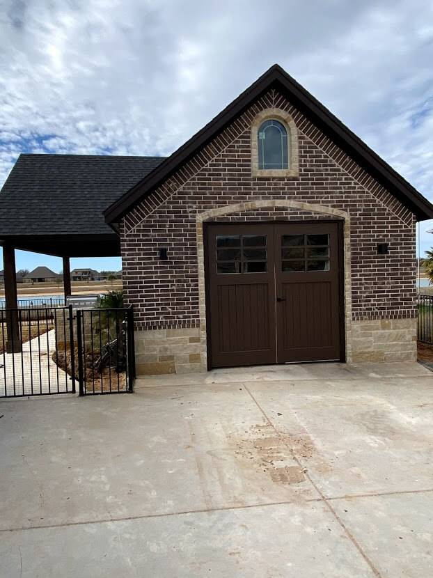Brick outbuilding with double wood doors and an arched window above them