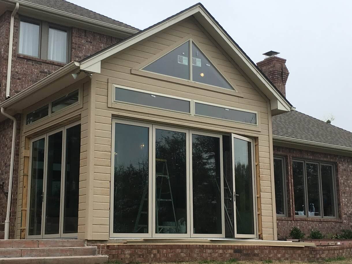 Home addition with a tall gable window and tall glass folding doors, photographed during construction