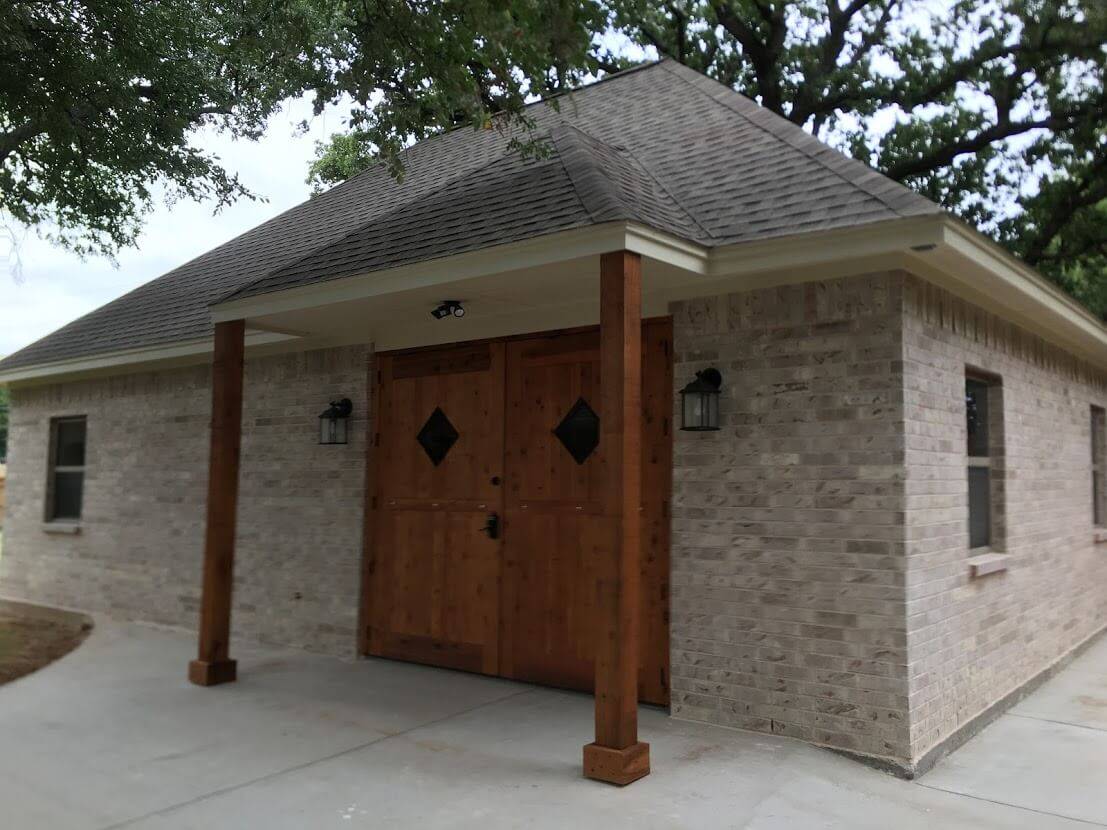 Brick building with double wood doors under a covered entry with cedar posts