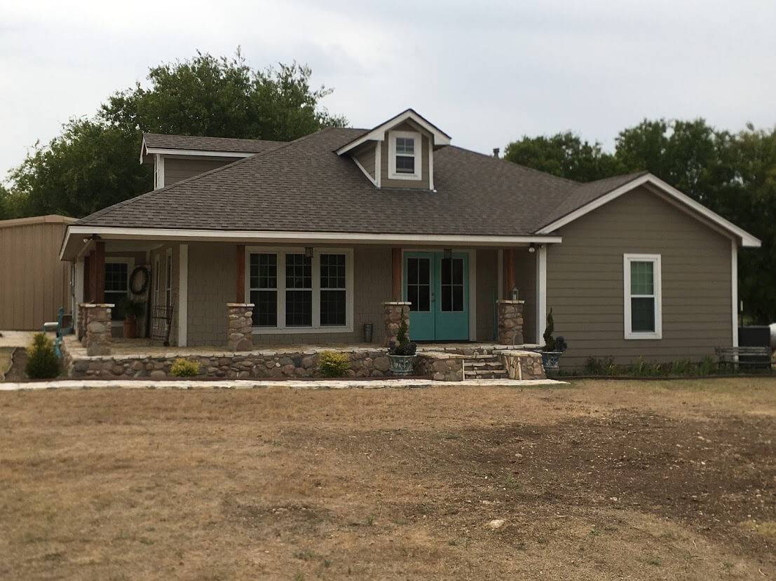 Single-story home with a stone-accented front porch, teal double doors and a dormer window